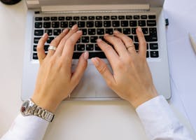 Hands typing on a sleek laptop keyboard in a bright, modern workspace. Ideal for business concepts.